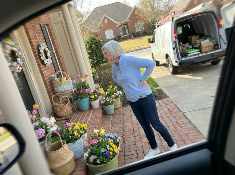 Retired woman admiring a finished spring porch decoration from the sidewalk