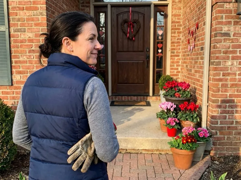 Woman stepping back to admire a finished seasonal porch decoration